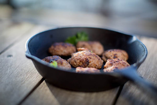Maple sausage frying up in a cast iron pan
